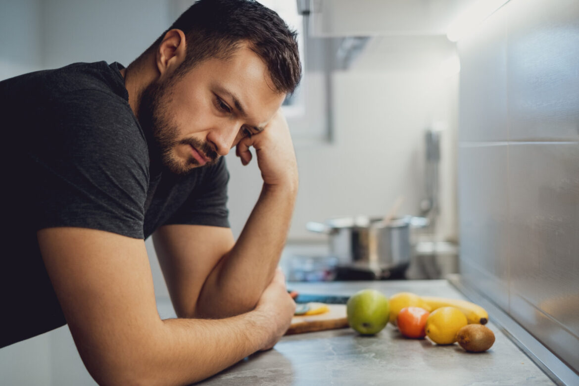 Sad man leaning on the kitchen countertop