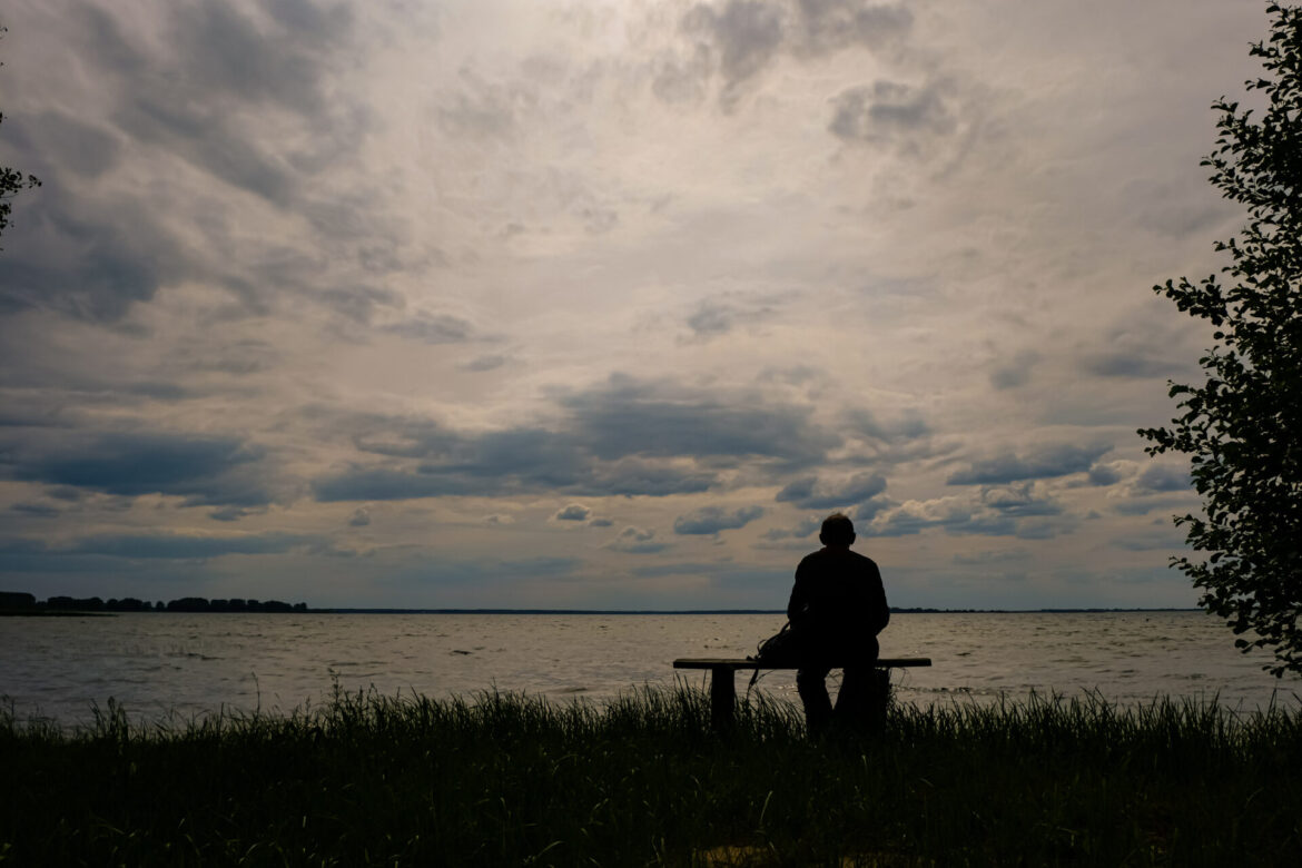 Person silhouette. The man 60 years is sitting on a wooden bench.