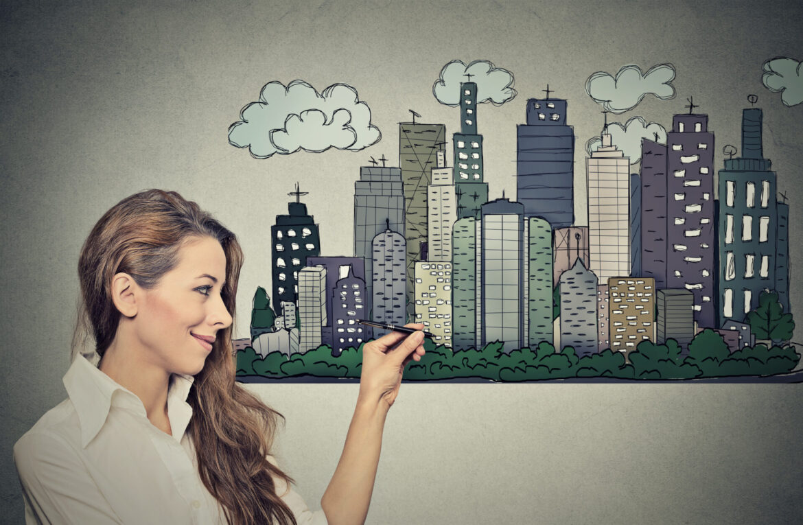 Woman drawing city skyline on grey wall background